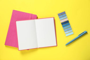 Kalem, not defterleri ve sarı arkaplanda renkli çıkartmalar, düz uzanma