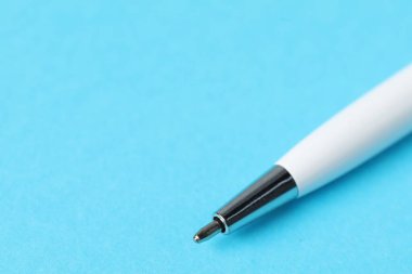 Açık mavi arka planda bir tükenmez kalem, makro görüş. Metin için boşluk