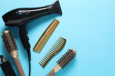 Açık mavi arka planda farklı saç şekillendirme araçları, düz yatış. Metin için boşluk