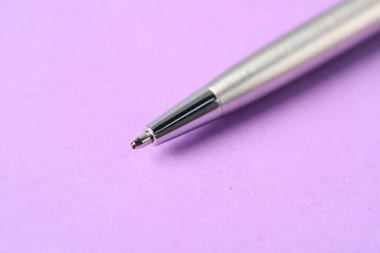 Mor arka planda şık bir kalem, makro görünüm. Metin için boşluk