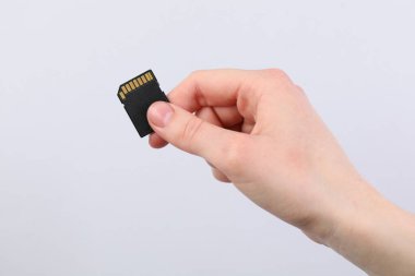 Açık gri arkaplanda SD hafıza kartı olan adam, yakın plan