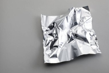 Açık gri arka planda buruşmuş alüminyum folyo parçası, üst manzara. Metin için boşluk