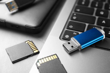 Flaş bellek, SD hafıza kartları, açık gri masadaki harici hard disk ve laptop, yakın plan
