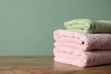 Ahşap masadaki temiz havlular yeşil arka plana karşı, yakın plan. Metin için boşluk