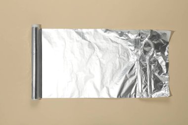 Bej arkaplanda alüminyum folyo rulosu, üst görünüm