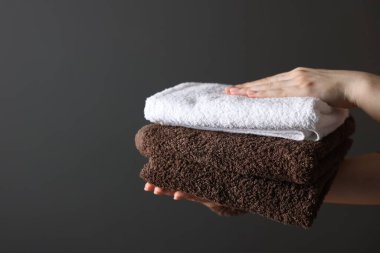 Koyu gri arka planda temiz havluları olan bir kadın, yakın plan. Metin için boşluk