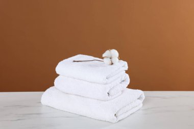 Temiz havlu ve pamuk çiçeği beyaz mermer masada kahverengi arka planda