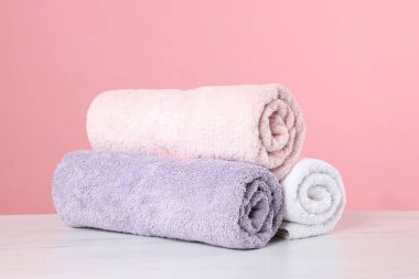 Pembe arka planda açık mermer masa üzerinde temiz havlular