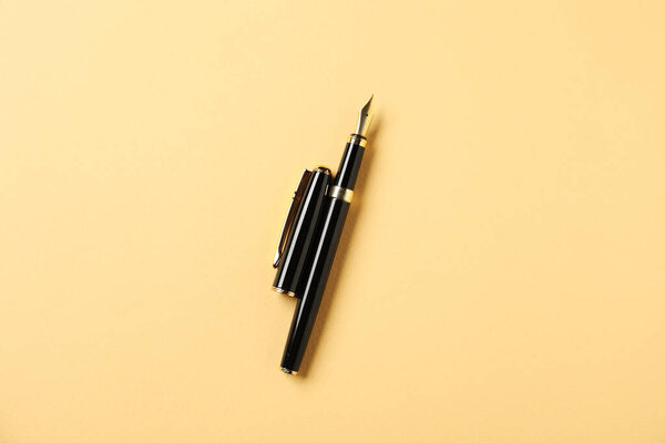 One fountain pen and lid on yellow background, top view