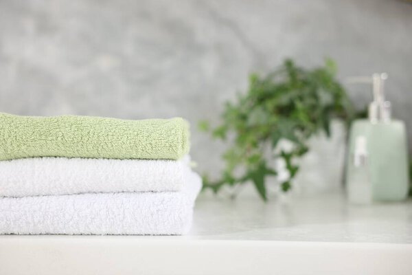 Stack of clean towels on white table indoors, closeup. Space for text