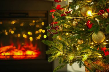 Evdeki şöminenin yanında at oyuncağı, diğer süsler ve festival ışıklarıyla süslenmiş güzel bir Noel ağacı, yakın çekim. Bokeh etkisi