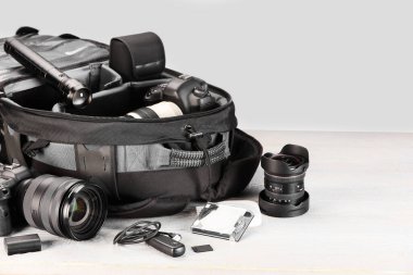 Profesyonel fotoğrafçının ekipmanı ve sırt çantası açık ahşap masada.