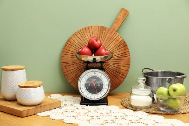 Kitchen scale, products and cooking utensils on wooden table