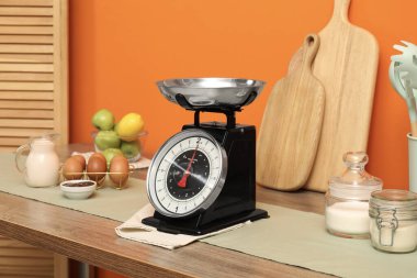 Kitchen scale, products and cooking utensils on wooden table