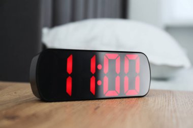 Dijital alarm saat 11 'de kapalı bir odada, komodinin yanında.