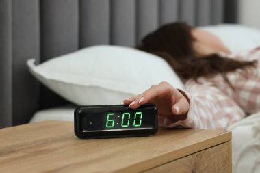 Kadın, başucundaki masanın dijital alarmını kapatıyor.