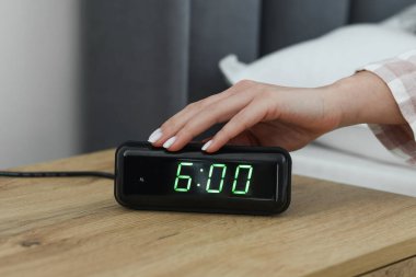 Kadın, başucundaki masanın dijital alarmını kapatıyor.