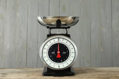 Mechanical kitchen scale with bowl on wooden table