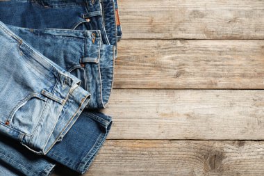 Different stylish jeans on wooden background, flat lay. Space for text