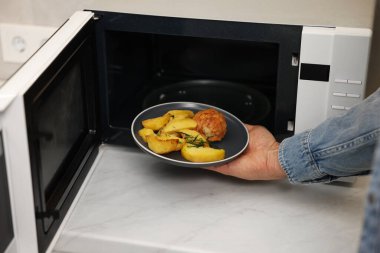 Yemek tabağını mikrodalgaya koyan adam, yakın plan.