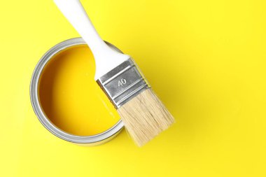 Sarı arka planda parlak boya ve fırça kutusu, üst manzara. Metin için boşluk