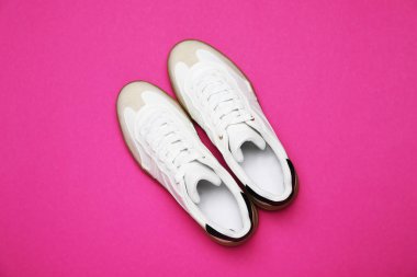 Pembe arka planda bir çift şık spor ayakkabı, düz yatış. Sıradan ayakkabılar.