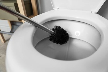 Cleaning toilet bowl with brush indoors, closeup