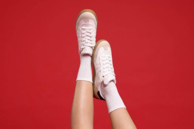 Kırmızı arka planda şık ayakkabılar giyen kadın, yakın plan.