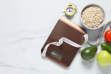 Elektronik mutfak ölçeği, mezura, alarm saati ve beyaz mermer masa üzerindeki ürünler, düz zemin. Metin için boşluk