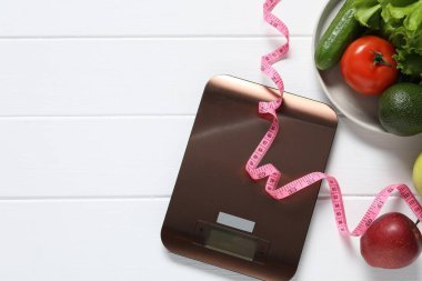 Elektronik mutfak ölçeği, mezura ve beyaz ahşap masa üzerindeki ürünler, düz yatak. Metin için boşluk