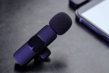 Lavalier mikrofon, kablosuz alıcısı ve siyah defteri olan akıllı telefon, yakın plan.