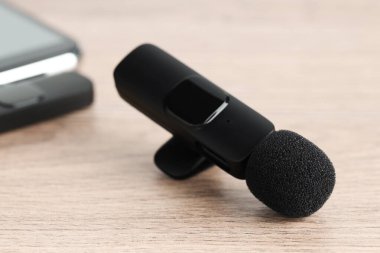 Lavalier mikrofon ve ahşap masada kablosuz alıcısı olan akıllı telefon.