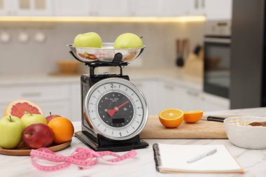 Mutfak pulları, meyveler, yulaf ezmesi, defter ve mezura.