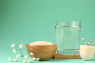 Kolajen tozu, kase, kepçe, bir bardak su ve turkuaz arka planda çingene çiçeği.