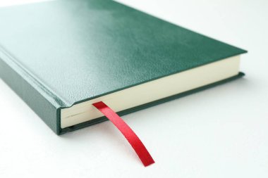 Beyaz masa üzerinde kırmızı kurdele yer imi olan kitap, yakın plan