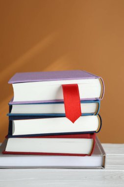 Kırmızı kurdele yer imi ve beyaz ahşap masa üzerinde kahverengi arkaplan ile renkli kitap