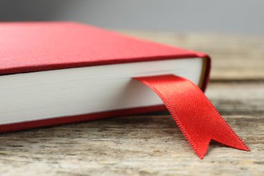 Ahşap masa üzerinde kırmızı kurdele yer imi olan bir kitap Gri arka plan, yakın plan