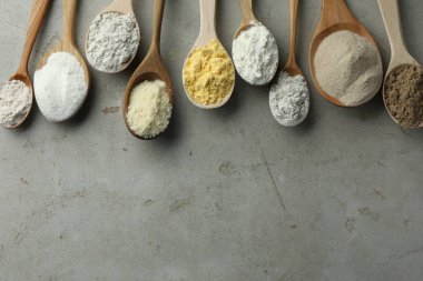 Açık gri masadaki kaşıklarda farklı türde un, düz. Metin için boşluk
