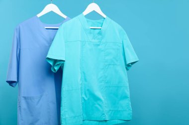 Sağlık çalışanları üniformalarını mavi arka plana asıyorlar.