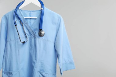 Gri arka planda steteskop takılı sağlık çalışanı üniforması. Metin için boşluk