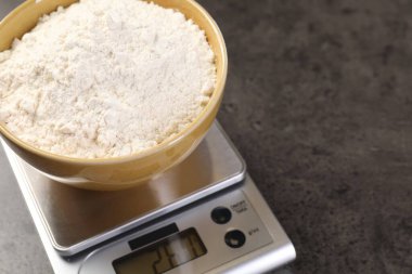 Dijital mutfak terazisi ve bir kase un, yakın plan. Metin için boşluk