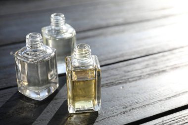 Siyah ahşap arka planda aromatik yağlı parfüm şişeleri, yakın plan. Metin için boşluk
