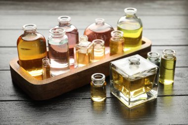Siyah ahşap arka planda aromatik yağlı parfüm şişeleri