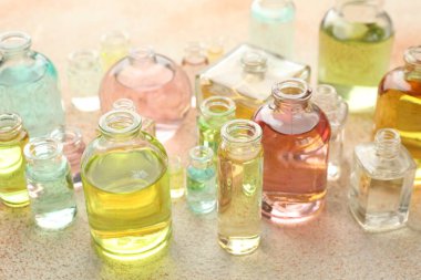 Bej desenli arka planda aromatik yağlı parfüm şişeleri, yakın plan.