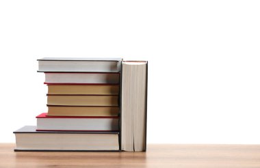 Beyaz arkaplana karşı ahşap masadaki eski kitaplar yığını