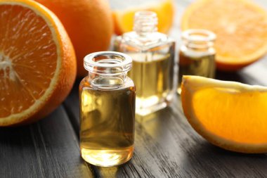 Siyah ahşap masa üzerinde aromatik esanslı yağ ve portakal dilimleri bulunan parfüm şişelerini aç. Yakın plan.