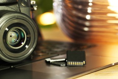 SD hafıza kartları, dizüstü bilgisayar ve fotoğraf makinesi masada, yakın plan.