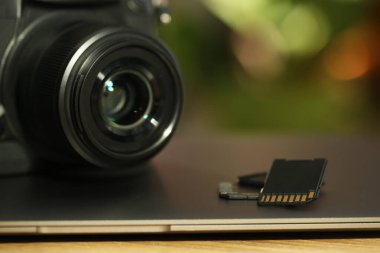 SD hafıza kartları, dizüstü bilgisayar ve fotoğraf makinesi masada, yakın plan.
