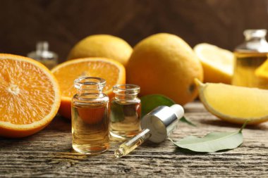 Aromatik esanslı parfüm şişelerini aç. Pipet, portakal ve yapraklar ahşap masada. Yakın plan.