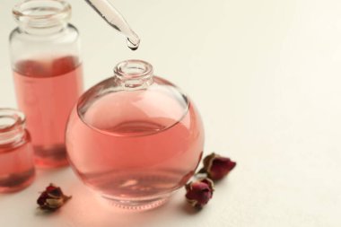 Beyaz masadaki açık parfüm şişesine yağ damlatıyor.